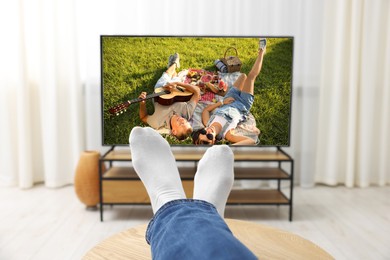 Image of Man watching movie on TV set at home