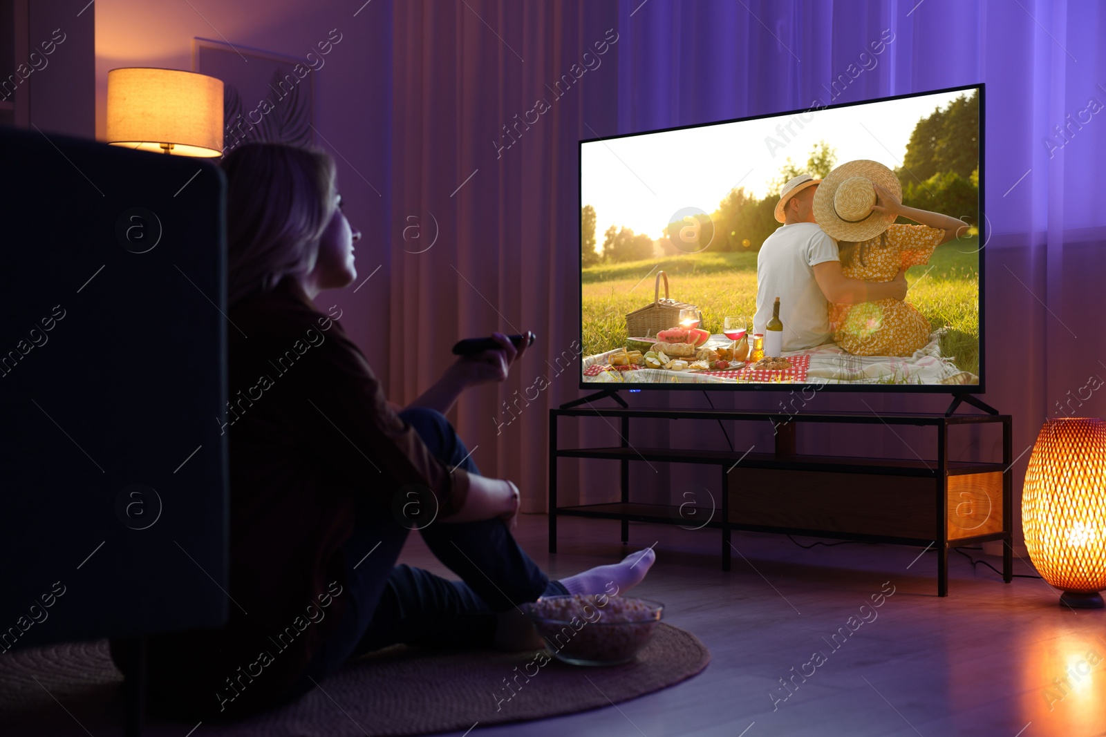 Image of Woman watching movie on TV set in room at night