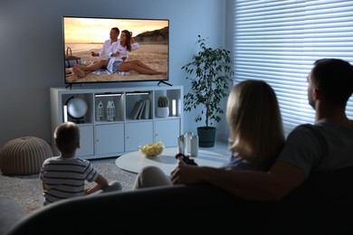 Image of Family watching movie on TV set at home