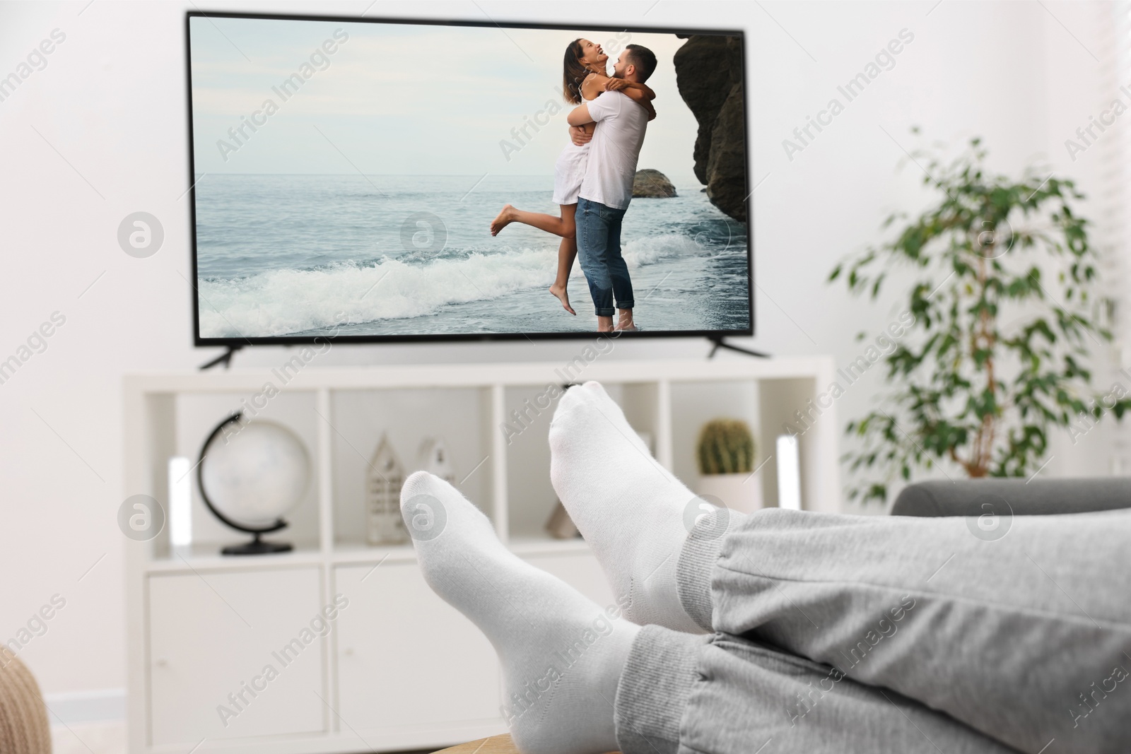 Image of Man watching movie on TV set at home