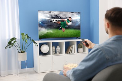 Image of Man watching soccer game on TV set at home