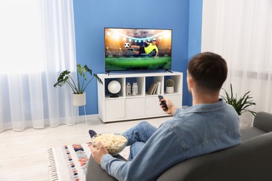 Image of Man watching soccer game on TV set at home