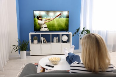 Image of Woman watching baseball game on TV set at home