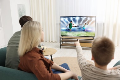 Image of Family watching soccer game on TV set at home