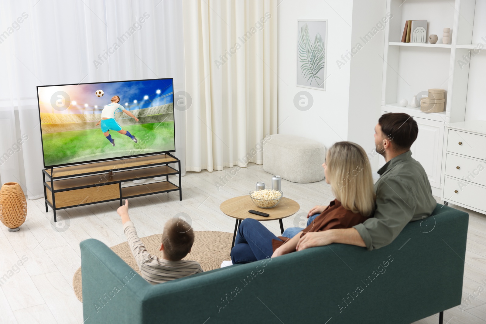 Image of Family watching soccer game on TV set at home