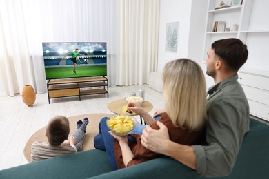 Image of Family watching soccer game on TV set at home