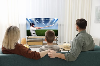 Image of Family watching baseball game on TV set at home