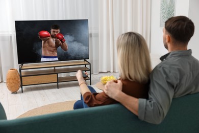 Image of Couple watching boxing fight on TV set at home