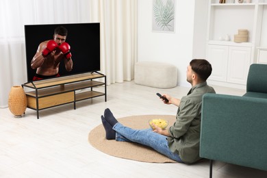 Image of Man watching boxing fight on TV set at home