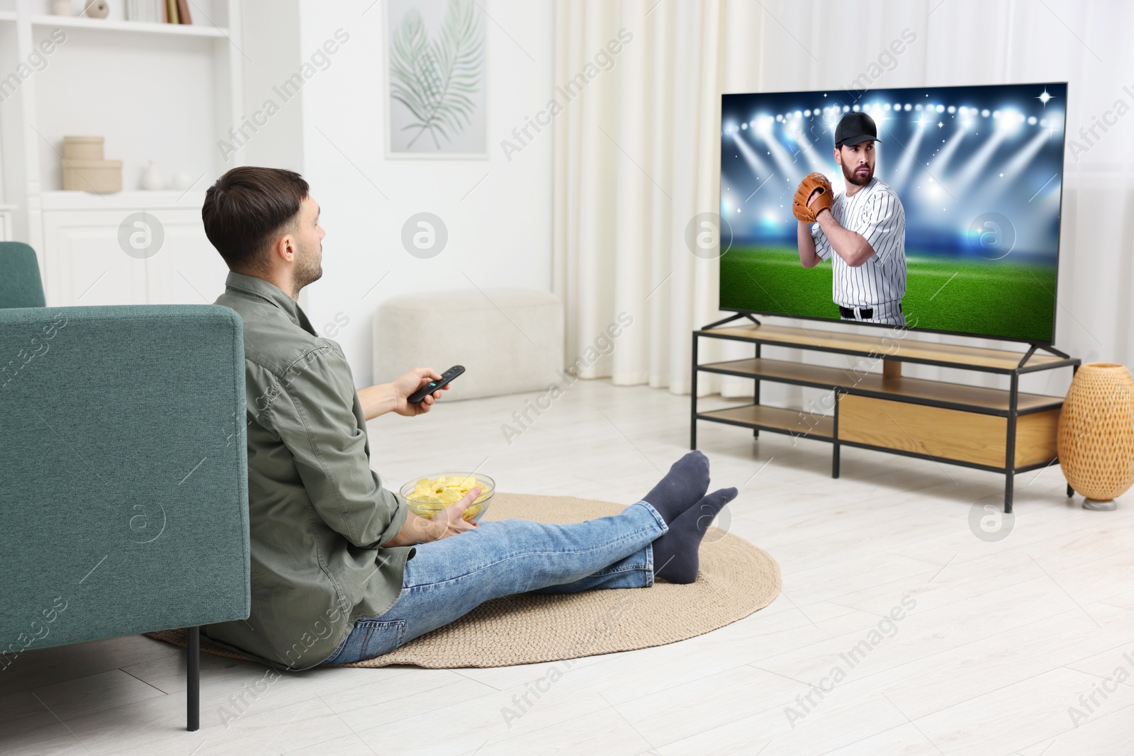 Image of Man watching baseball game on TV set at home