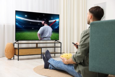 Image of Man watching baseball game on TV set at home