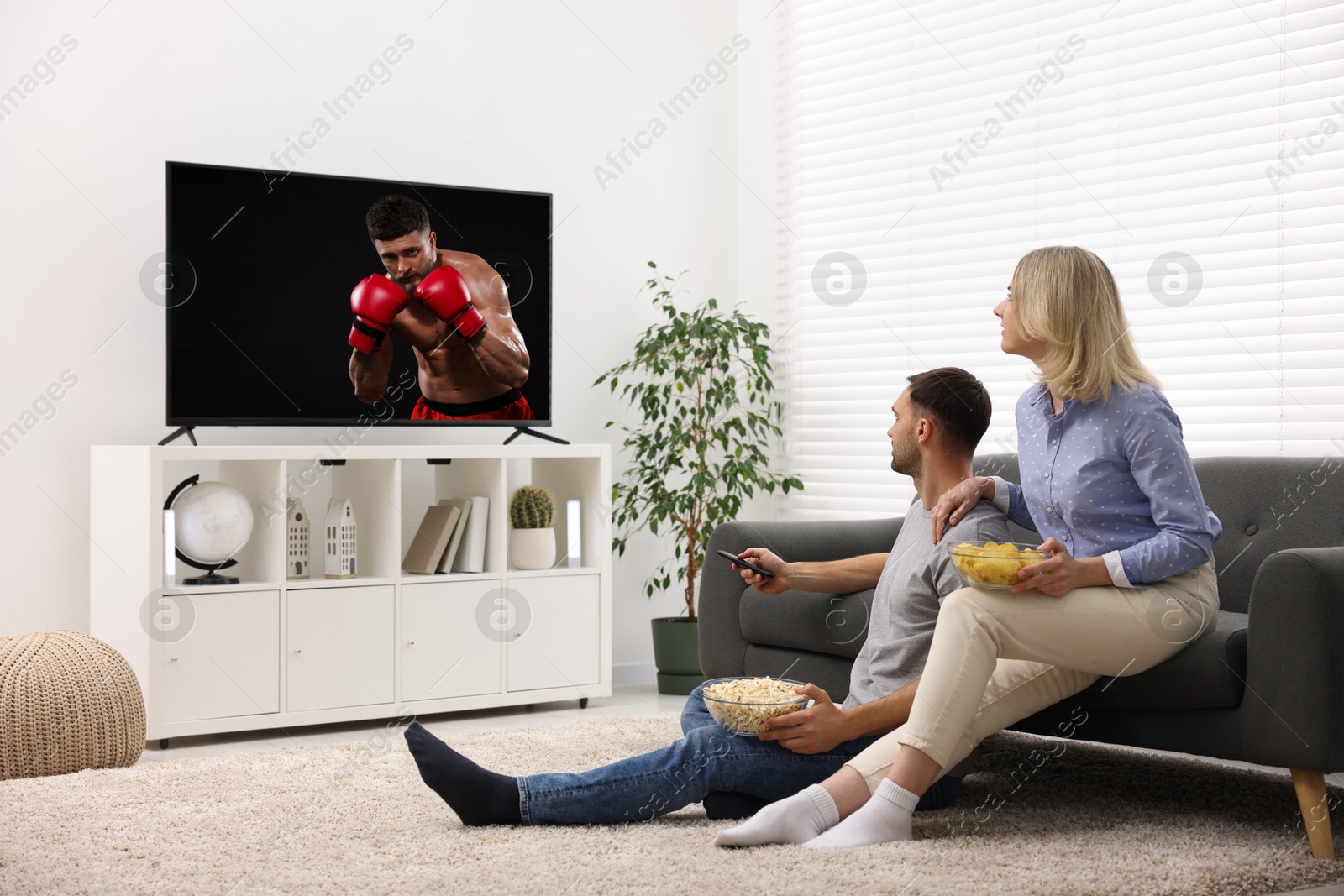 Image of Couple watching boxing fight on TV set at home