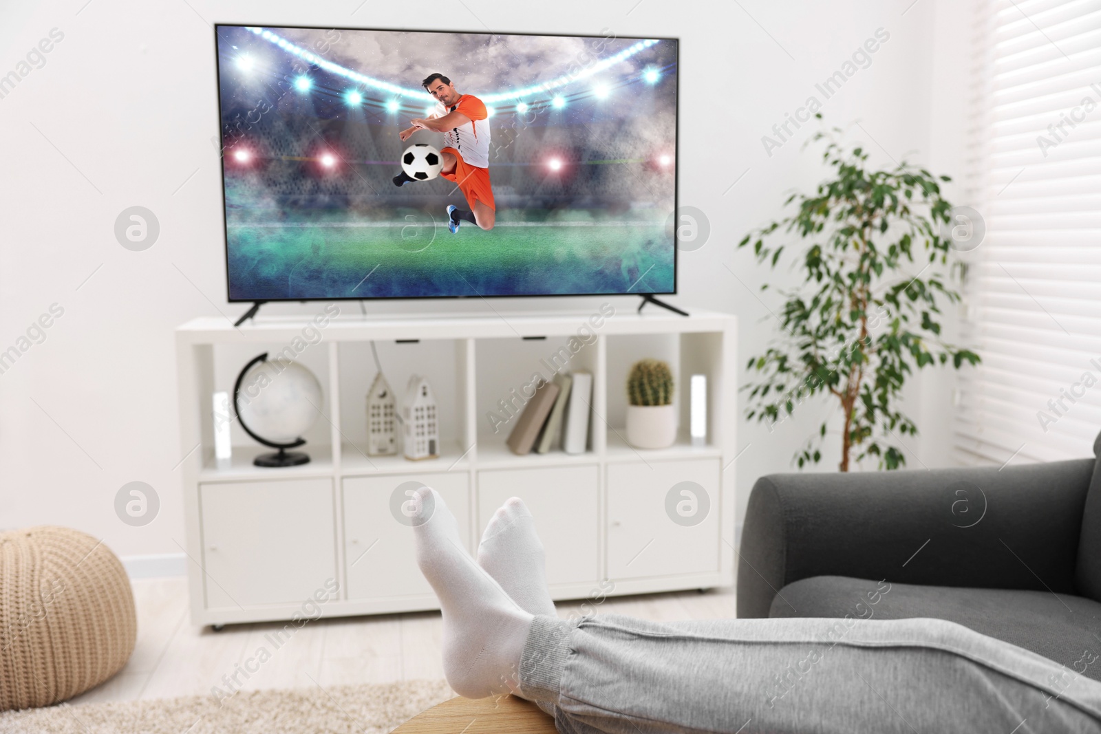 Image of Man watching soccer game on TV set at home, closeup