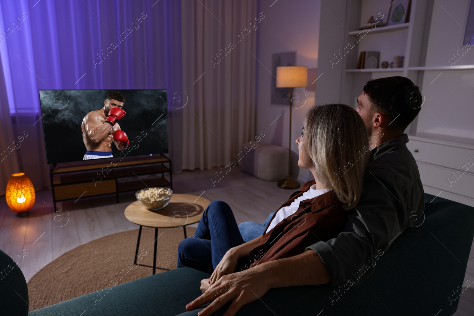 Image of Couple watching boxing fight on TV set at home