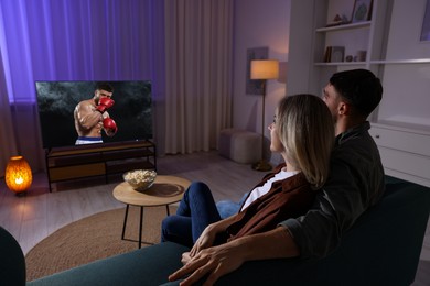 Image of Couple watching boxing fight on TV set at home