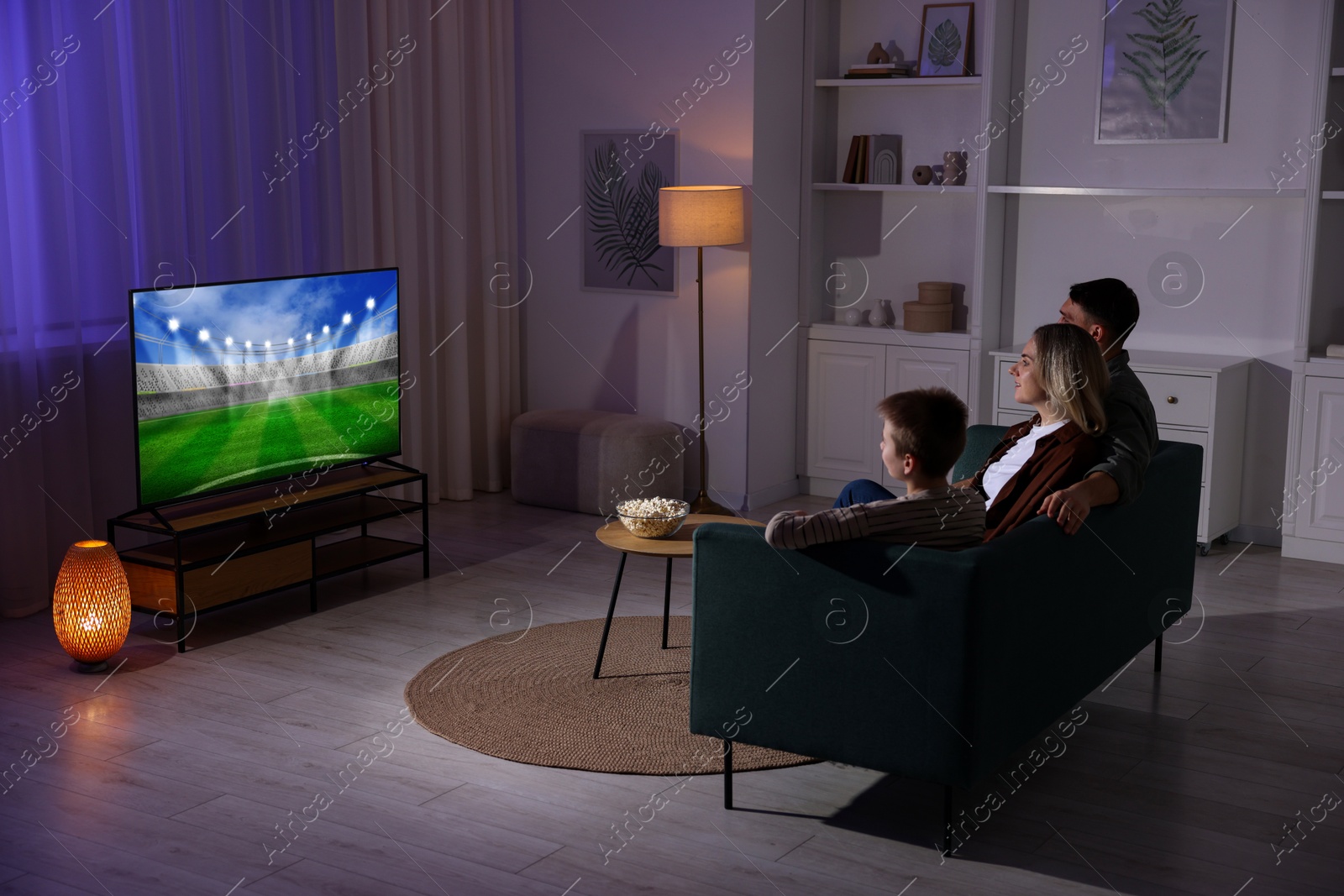 Image of Family watching sport game on TV set at home