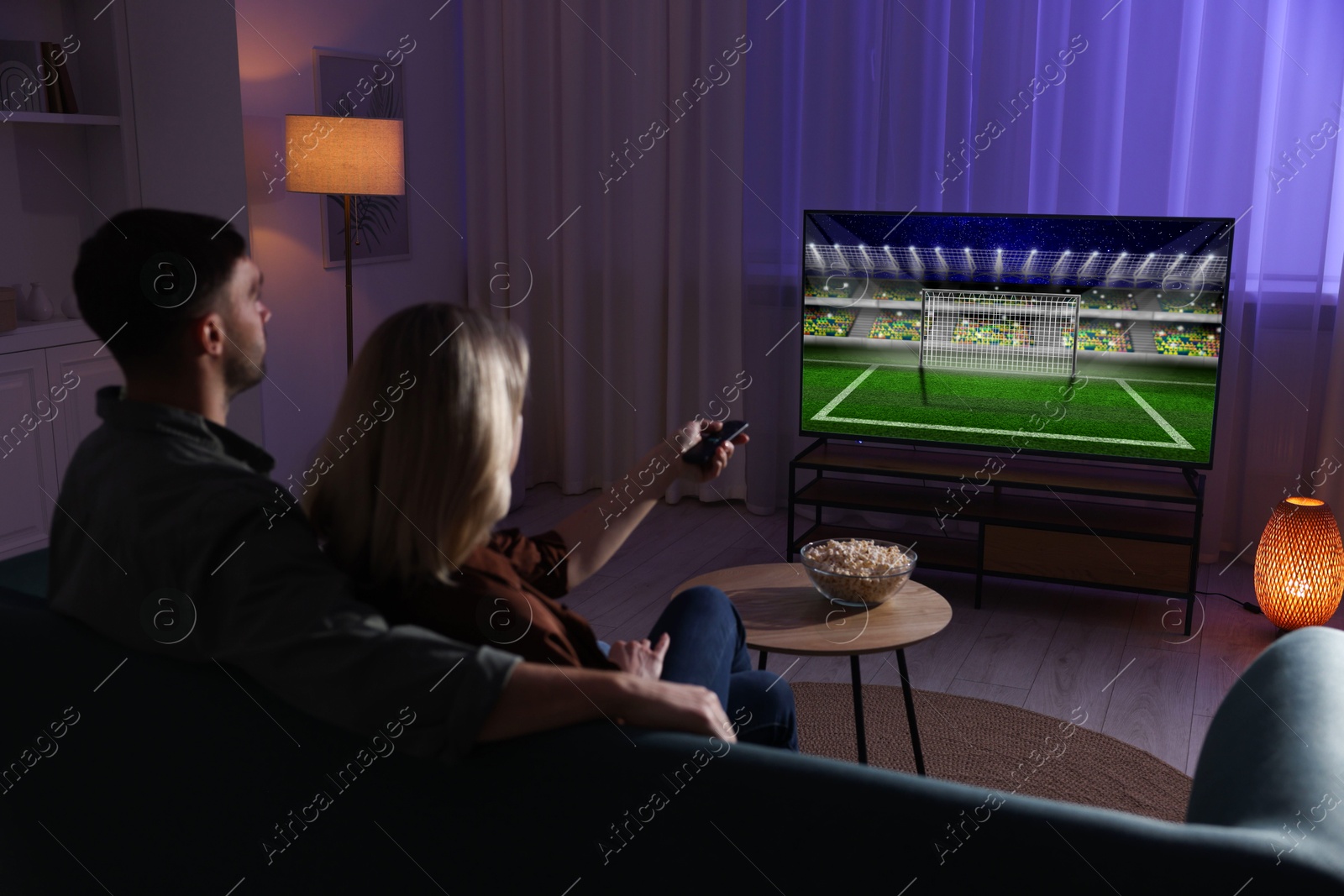 Image of Couple watching sport game on TV set at home