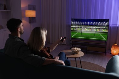 Image of Couple watching sport game on TV set at home