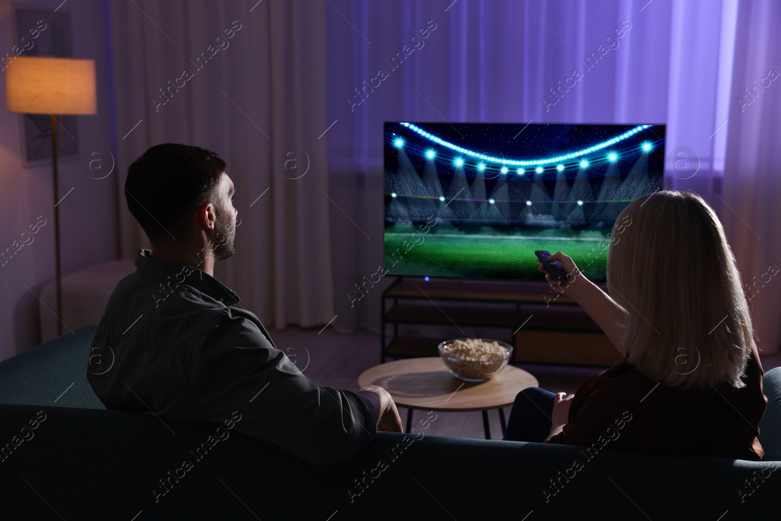 Image of Couple watching sport game on TV set at home