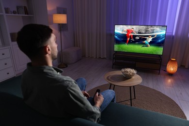 Image of Man watching soccer game on TV set at home