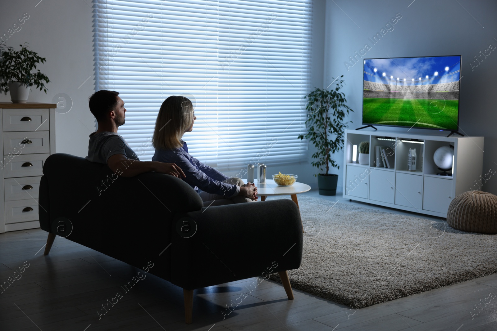 Image of Couple watching sport game on TV set at home