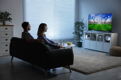 Image of Couple watching sport game on TV set at home