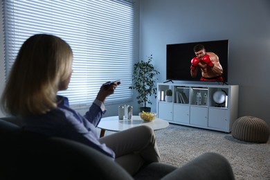 Image of Woman watching boxing fight on TV set at home