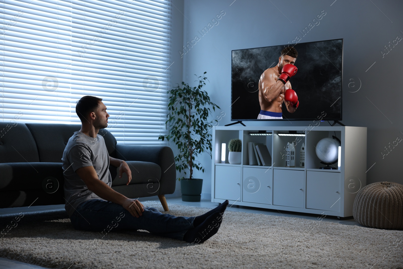 Image of Man watching boxing fight on TV set at home