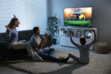 Image of Family watching soccer game on TV set at home