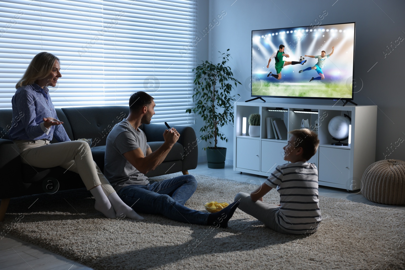 Image of Family watching soccer game on TV set at home