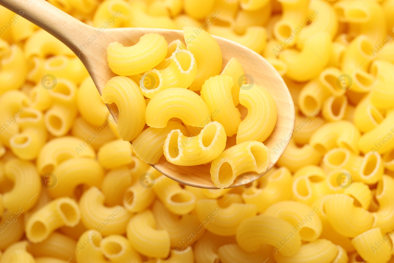 Photo of Raw horns pasta and spoon as background, top view