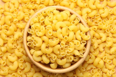 Photo of Raw horns pasta and bowl as background, top view