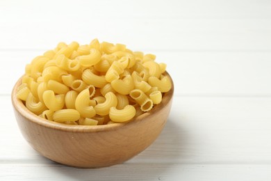 Photo of Raw horns pasta in bowl on white wooden table, closeup