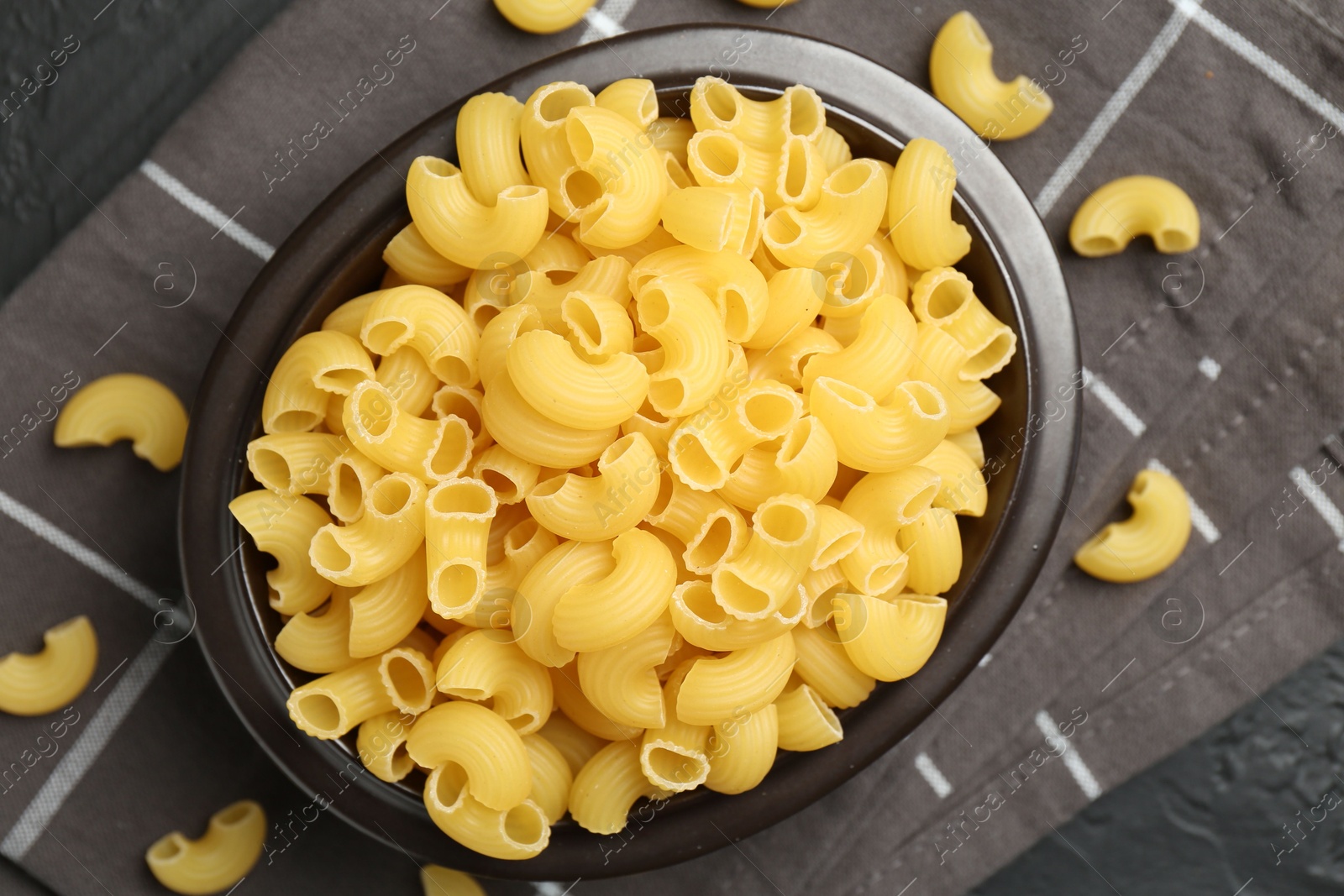 Photo of Raw horns pasta in bowl on table, top view