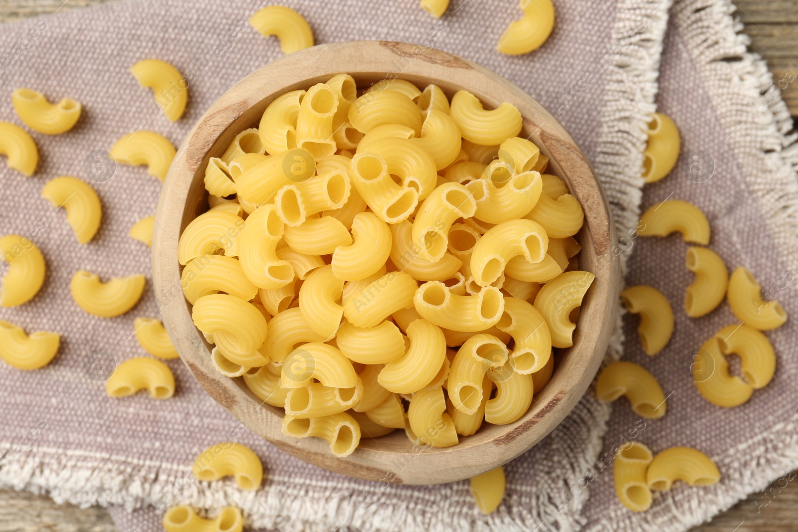 Photo of Raw horns pasta in bowl on table, top view