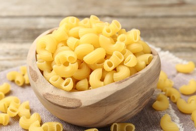 Photo of Raw horns pasta in bowl on table, closeup