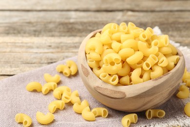 Photo of Raw horns pasta in bowl on table, closeup. Space for text