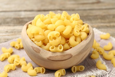 Photo of Raw horns pasta in bowl on table, closeup