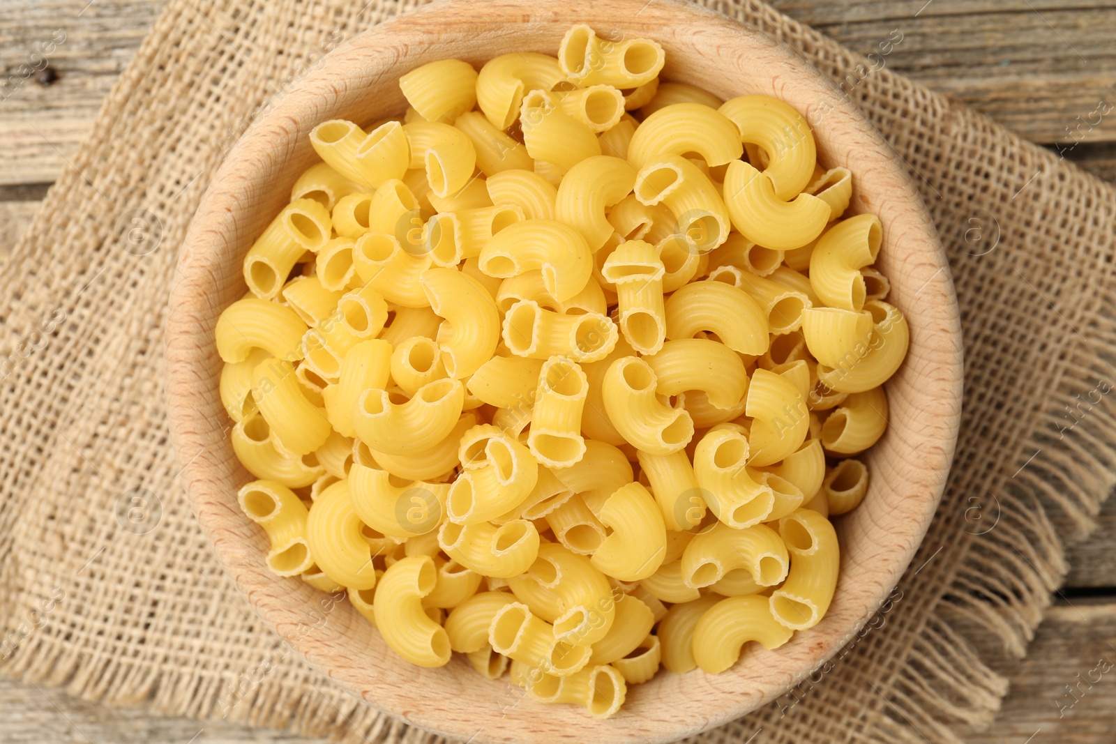 Photo of Raw horns pasta in bowl on table, top view