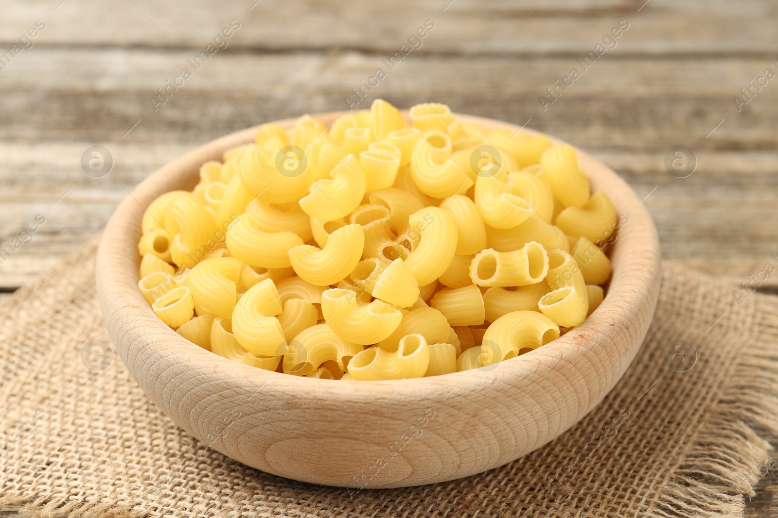 Photo of Raw horns pasta in bowl on table, closeup