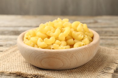 Photo of Raw horns pasta in bowl on table, closeup