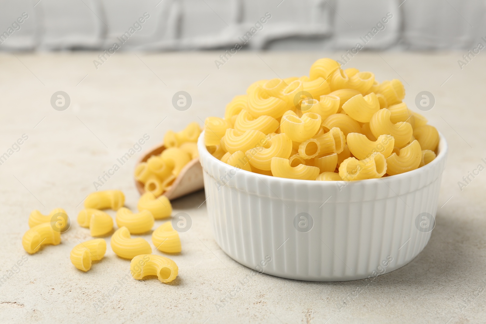 Photo of Raw horns pasta in bowl on gray textured table, closeup. Space for text