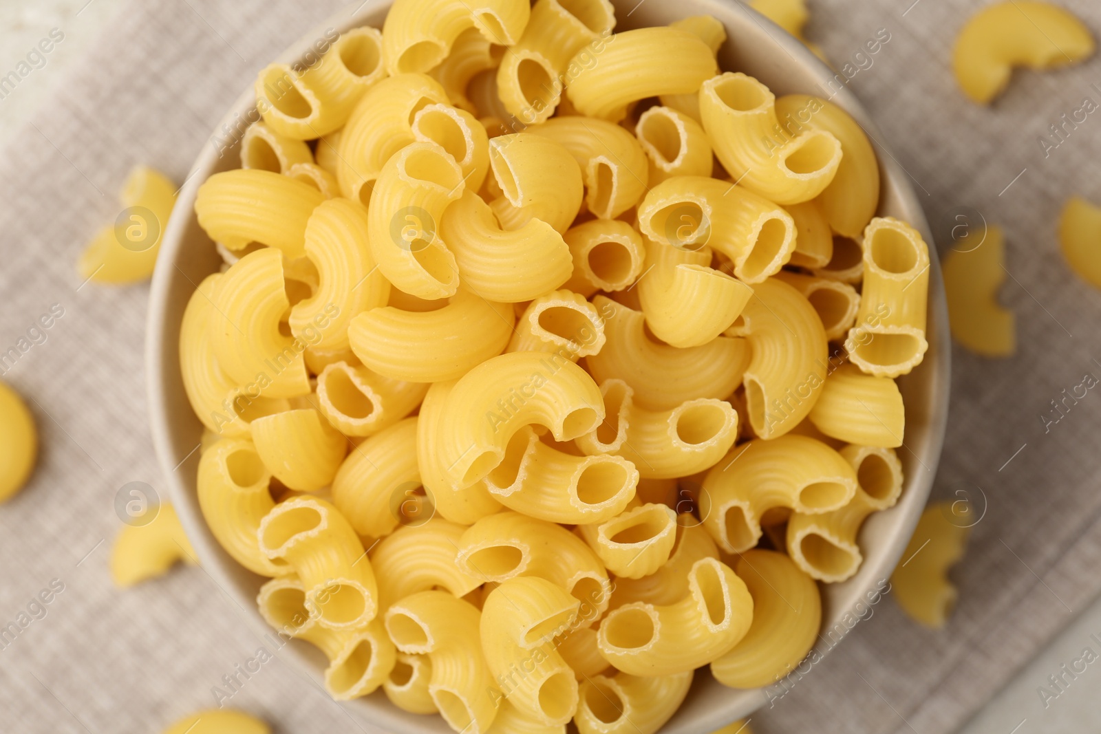 Photo of Raw horns pasta in bowl on table, top view