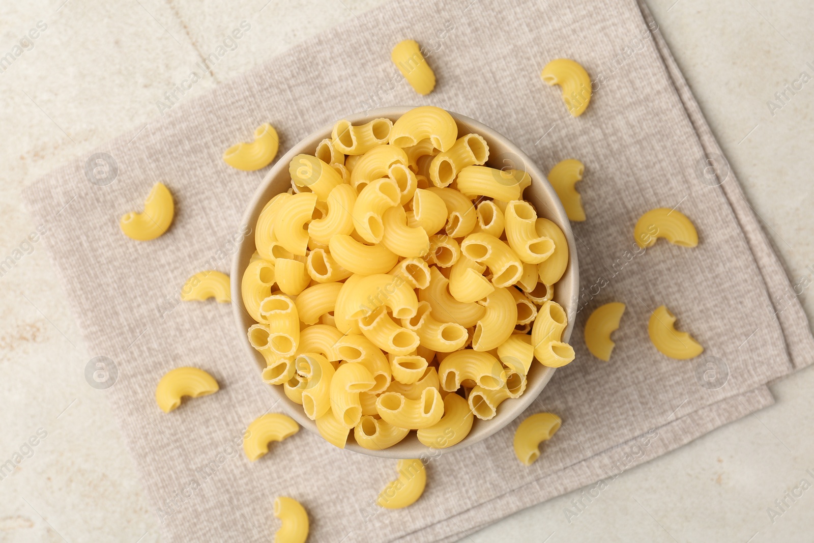 Photo of Raw horns pasta in bowl on gray table, top view