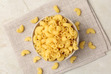 Photo of Raw horns pasta in bowl on gray table, top view