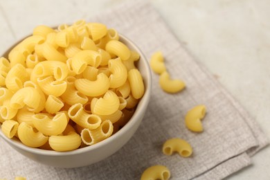 Photo of Raw horns pasta in bowl on gray table, closeup. Space for text