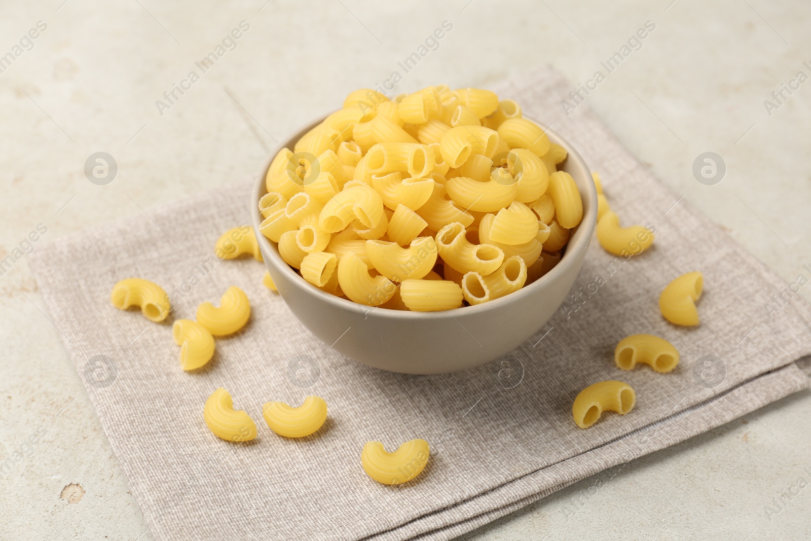 Photo of Raw horns pasta in bowl on gray textured table