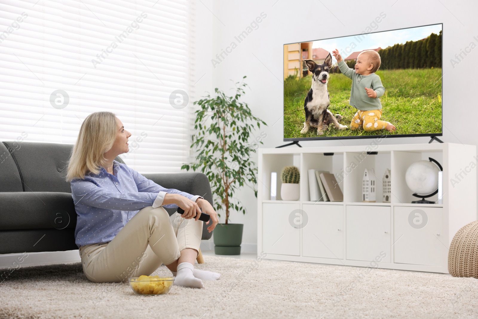 Image of Woman watching movie on TV set at home