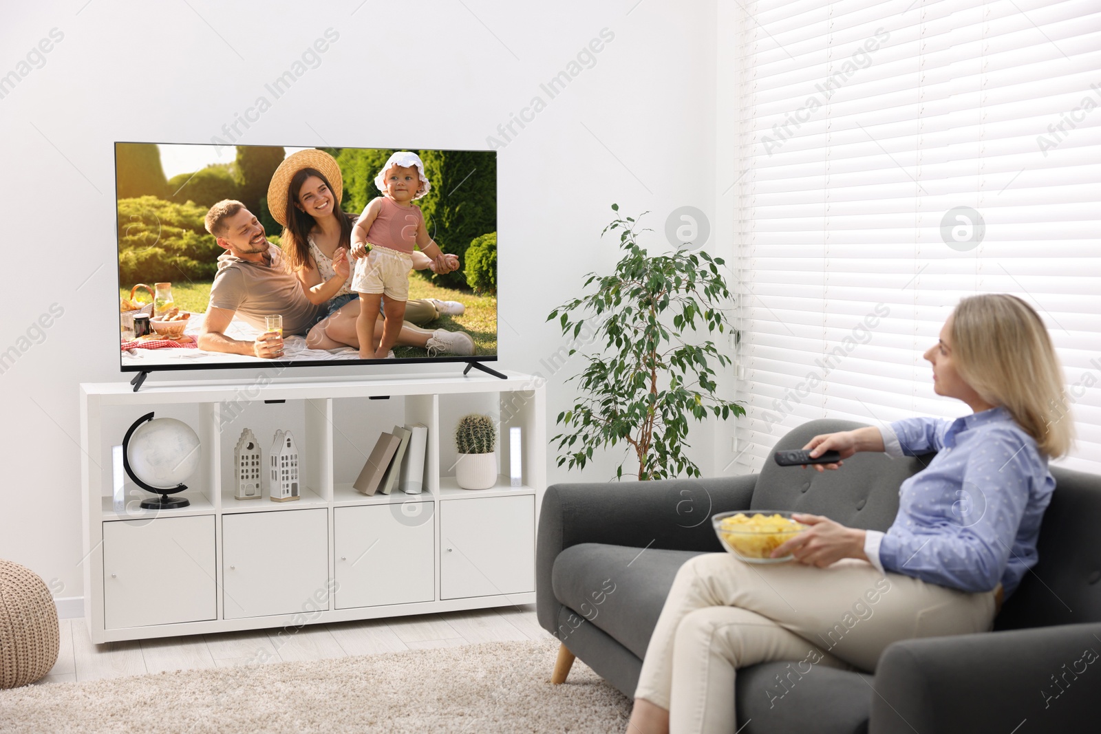 Image of Woman watching movie on TV set at home