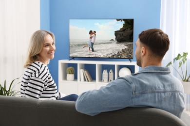 Image of Couple watching movie on TV set at home